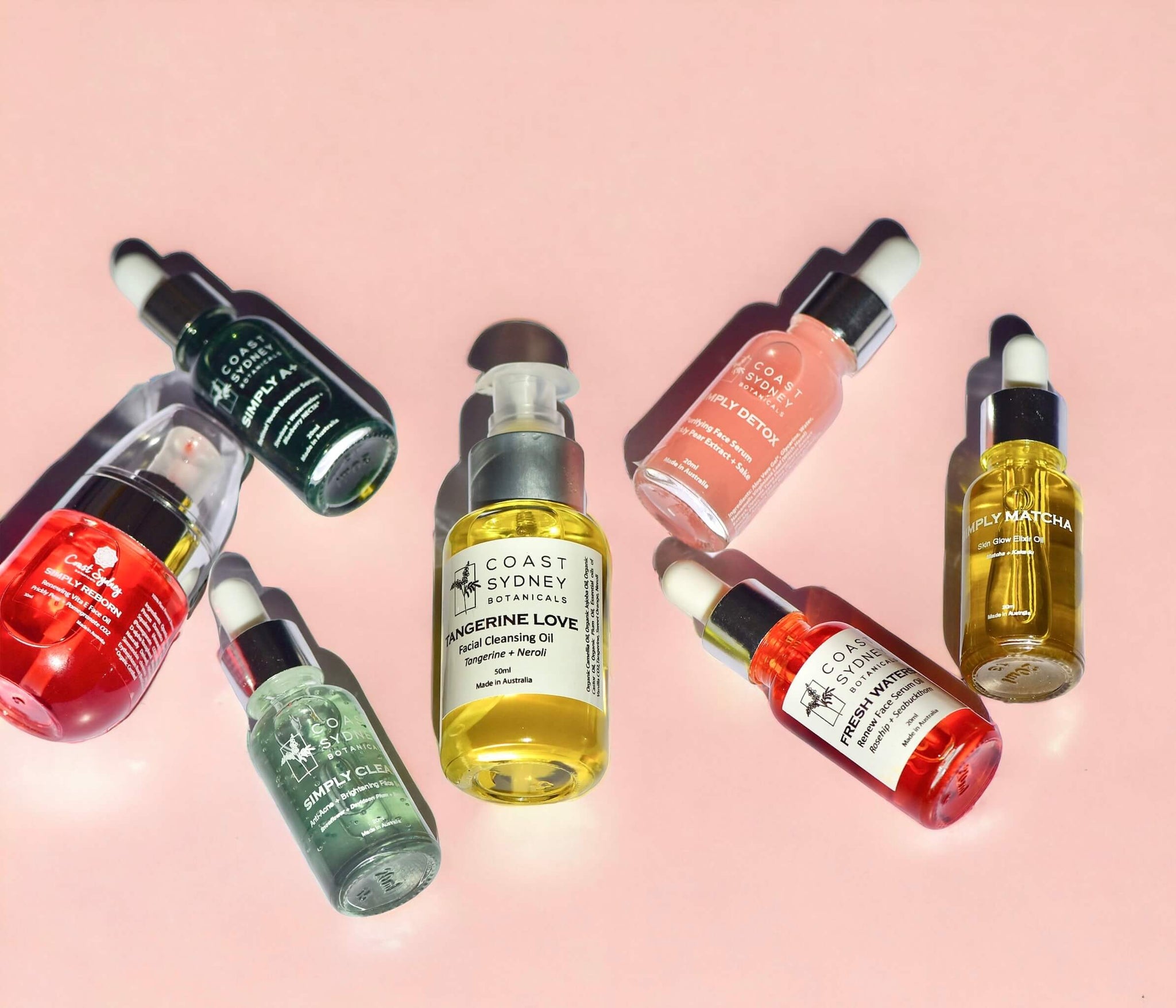 Collection of best facial oils and serums on a pink background