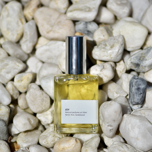 'Joy' oil perfume captured on a background of white rocks.